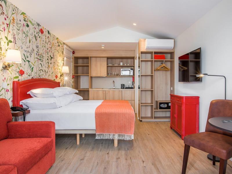 Modern hotel room with double bed, red armchair, and stylish wall design.