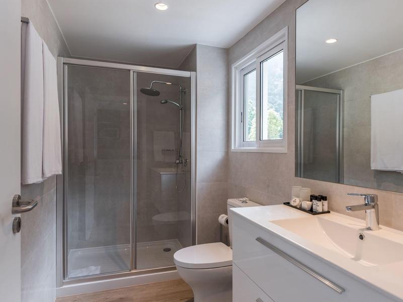 Modern bathroom interior with shower, toilet, and sink under a window.