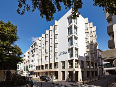 Edificio di hotel moderno con molte finestre e linee pulite su una strada soleggiata.