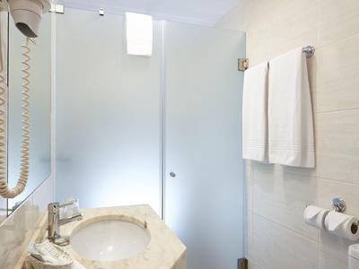 Bagno d'hotel luminoso con lavabo in marmo, asciugamani e porta in vetro smerigliato