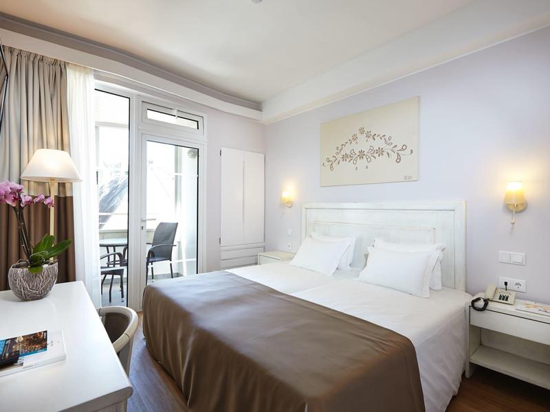 Camera d'hotel moderna con letto matrimoniale, scrivania, balcone e luce naturale.