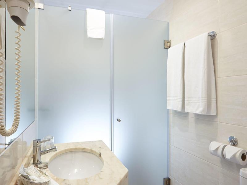Bagno d'hotel luminoso con lavabo in marmo, asciugamani e porta in vetro smerigliato