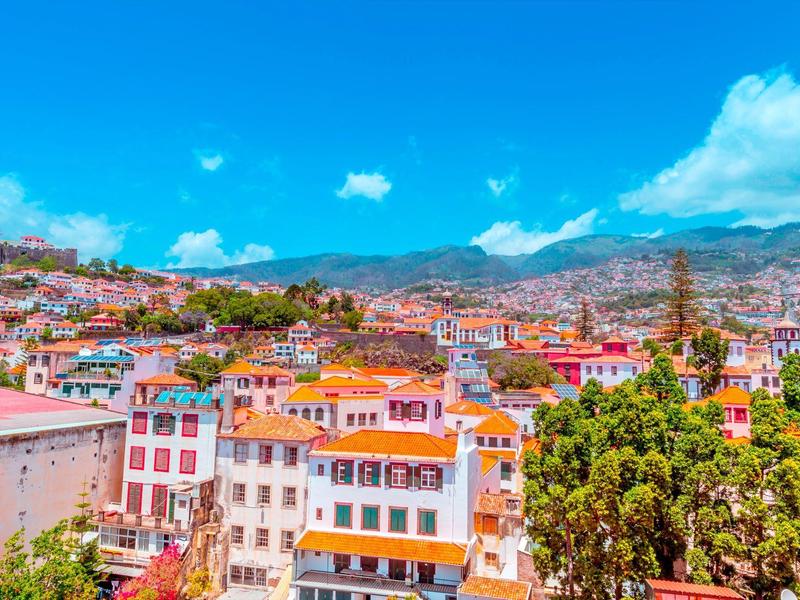 Veduta della città con edifici colorati sotto un cielo azzurro limpido in un paesaggio montano.
