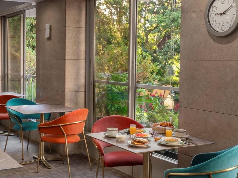 Accogliente area colazione con sedie colorate e vista sul verde esterno.