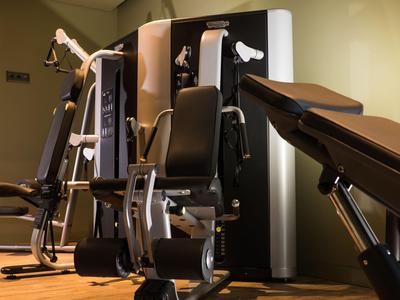 Modern fitness equipment in a hotel gym with wooden flooring and subdued lighting.