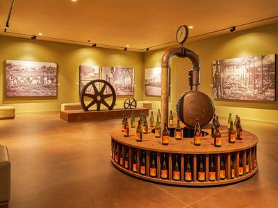 Museum mit historischen Maschinen, großen Walzen und ausgestellten kleinen Flaschen auf rundem Podest.