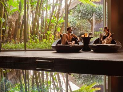 Zwei Personen sitzen in schwarzer Lounge-Möbel vor großem Fenster mit Blick auf grünen Garten.