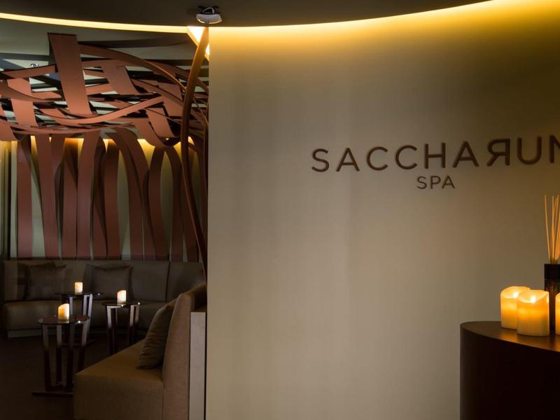 Innenraum eines Spabereichs mit indirekter Beleuchtung, Holzdekor und Kerzen auf einem Tisch.