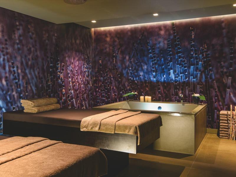 Ein Wohnzimmer mit dunklem Sofa, Kissen, Tisch und gemusterter blauer Wandgestaltung.