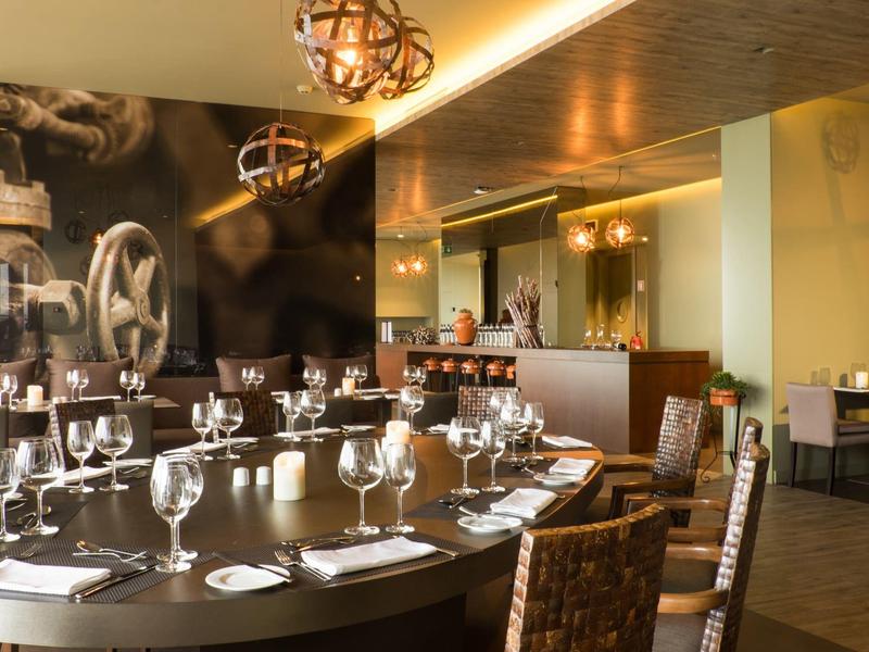 Elegantes Restaurant mit rundem Holztisch, gedeckten Gläsern und modernem Industrie-Design.