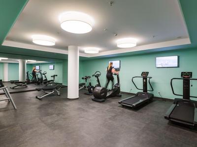 Salle de fitness avec tapis de course, vélos et équipements d'entraînement dans un design moderne.