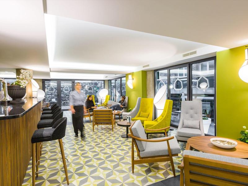 Modern eingerichteter Raum mit gelben Wänden, gemustertem Boden und gelben Ohrensesseln.