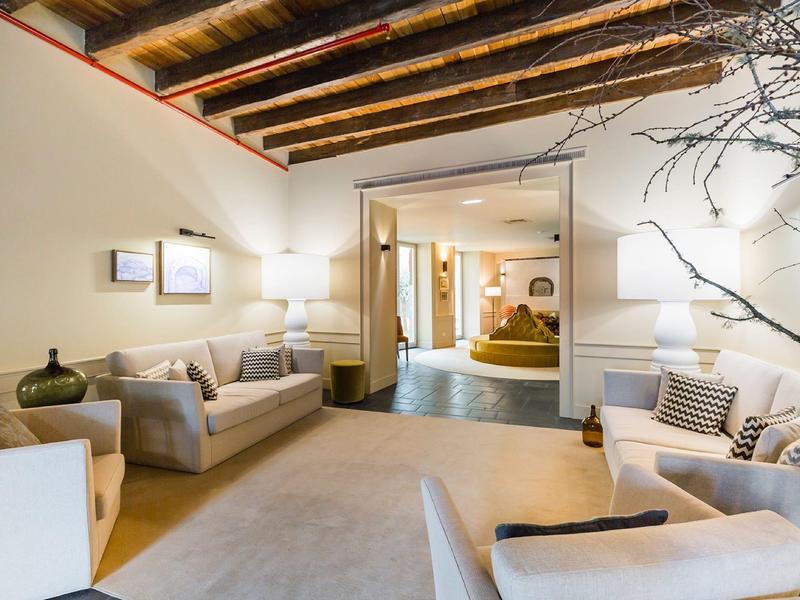 Helles Wohnzimmer mit Holzbalkendecke, zwei Sofas, Teppich und minimalistischer Dekoration.