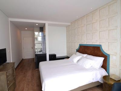 Nowoczesny pokój hotelowy z podwójnym łóżkiem, telewizorem i drewnianą podłogą.