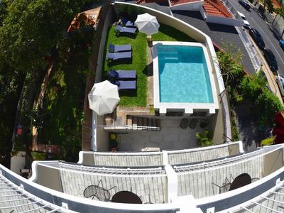 Basen i leżaki na tarasie hotelu z widokiem na ulicę.