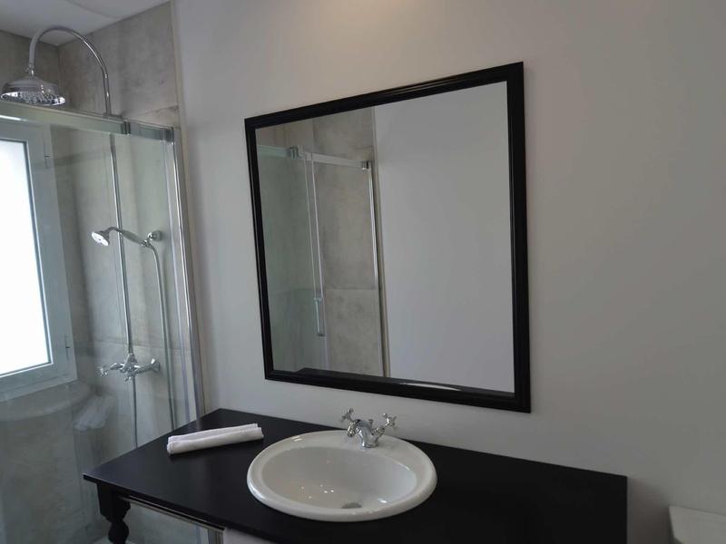 Nowoczesna łazienka z umywalką, dużym lustrem i prysznicem oświetlonym światłem dziennym.