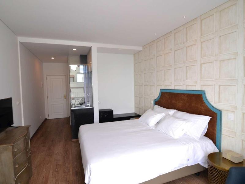 Nowoczesny pokój hotelowy z podwójnym łóżkiem, telewizorem i drewnianą podłogą.