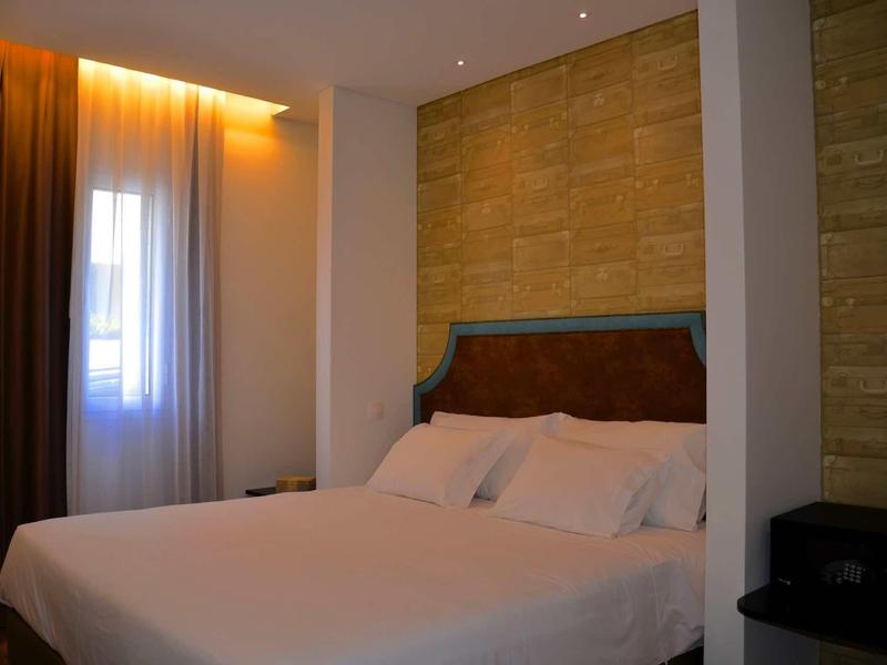 Przytulny pokój hotelowy z dużym łóżkiem, ceglaną ścianą i miękkim oświetleniem.