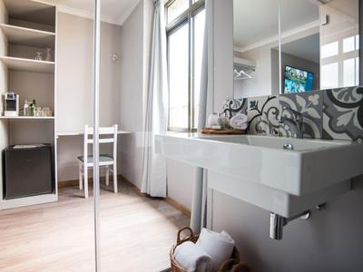 Habitación de hotel moderna y luminosa con ventana grande, lavabo y escritorio con silla.
