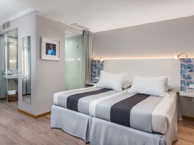 Habitación de hotel moderna con cama doble, paredes grises y suelo de madera.