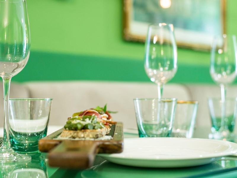 Primer plano de una mesa puesta con vasos y una tabla de madera con comida en un restaurante.