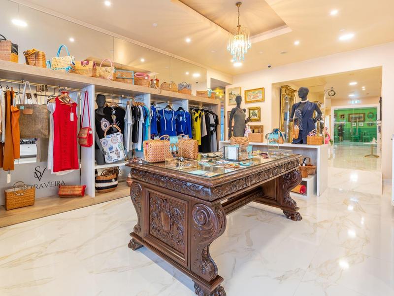 Tienda de ropa de hotel con mesa de billar antigua y prendas colgadas en percheros.