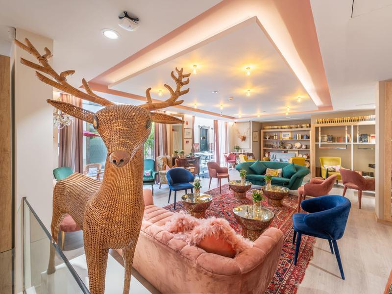 Área de salón acogedor de hotel con muebles y ciervo decorativo en primer plano.