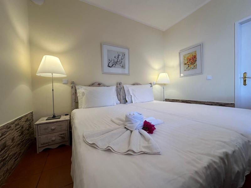 Hell eingerichtetes Schlafzimmer mit großem Bett, weißen Kissen und dekorativer Stofffigur.