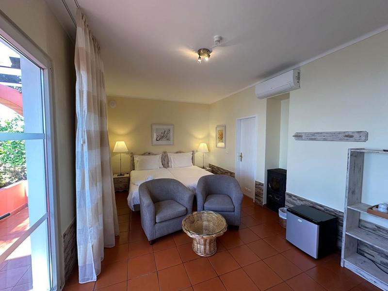 Gemütliches Schlafzimmer mit zwei Sesseln, Doppelbett, Nachttischlampen und offener Terrassentür.