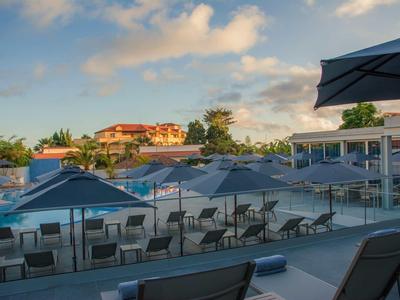 Buitenterras met tafels, stoelen en parasols onder een deels bewolkte lucht.