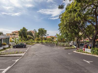Großer Parkplatz mit mehreren Autos vor einem Hotel bei bewölktem Himmel.