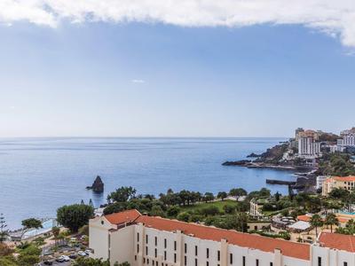Kuststad met gebouwen die uitkijken over een kalme zee onder een deels bewolkte lucht.