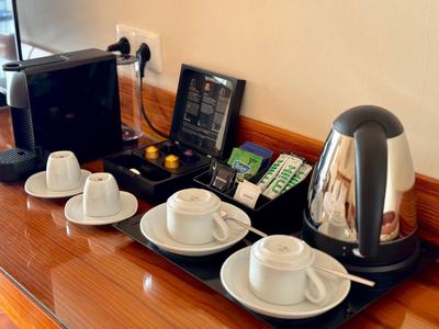 Stacja do herbaty i kawy z filiżankami, czajnikiem, torebkami herbaty i ekspresem do kawy na drewnianym stole.