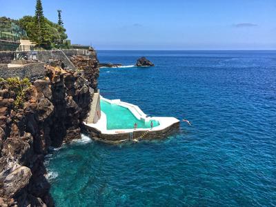 Piscina verde su rocce sopra il mare blu sotto un cielo limpido