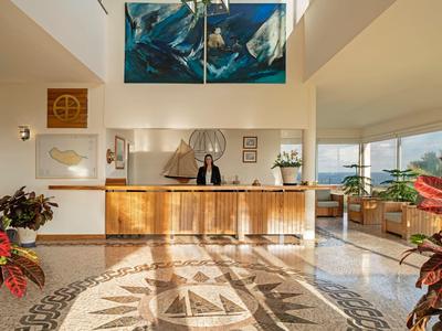 Jasna lobby hotelowa z nowoczesnym recepcją i dużą wzorzystą marmurową podłogą.