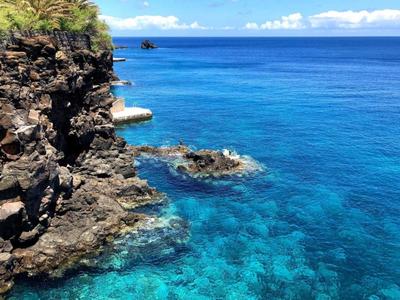Czyste, niebieskie morze obok skalistych klifów pod słonecznym niebem.