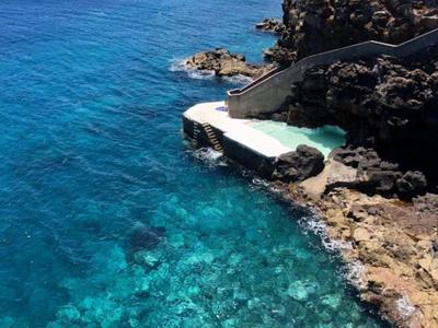 Czyste niebieskie morze przy skalistym wybrzeżu z małym betonowym pomostem i schodami