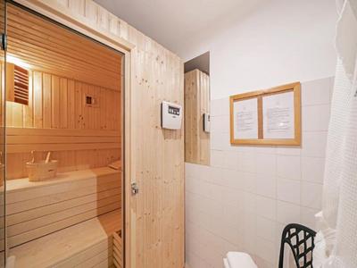 Widok wnętrza strefy wellness z sauną, drewnianymi drzwiami i białymi ścianami.