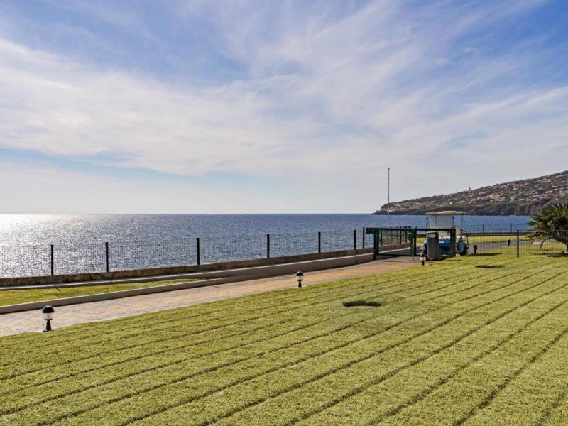 Zielony trawnik z drogą i widokiem na morze pod błękitnym niebem z chmurami.