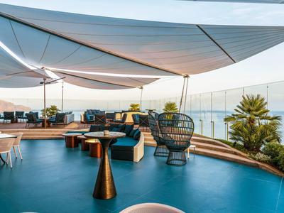 Moderní střešní terasa s odpočinkovou zónou a slunečními plachtami s výhledem na moře