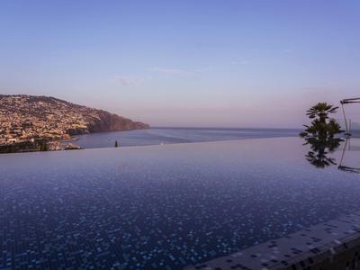 Infinity bazén s výhledem na pobřežní město a moře za jasné oblohy