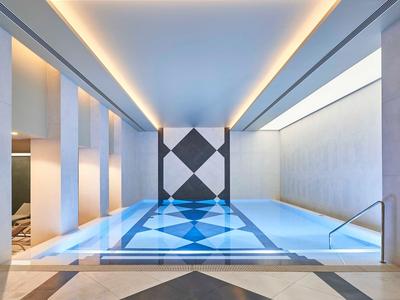 Moderní vnitřní bazén s geometrickým vzorem a ambientním osvětlením stropu.