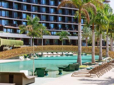 Moderní venkovní bazén s palmami a lehátky před hotelem