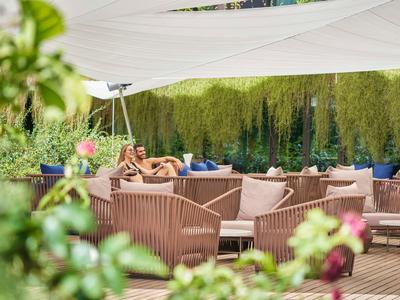 Pohodlná venkovní oblast s hnědými křesly a slunečními plachtami na terase.