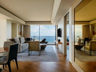 Moderně zařízený hotelový pokoj s posezením a velkým oknem s výhledem na moře