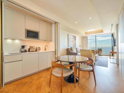 Moderní hotelový pokoj s kuchyňským koutem, jídelním koutem a posezením s výhledem na moře.