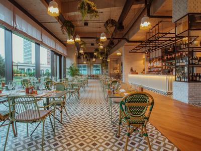 Moderně zařízená hotelová restaurace s velkými okny a vzorovanou podlahou.