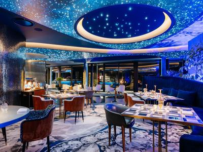 Elegantní restaurace s hvězdnou oblohou na stropě a moderním interiérem.