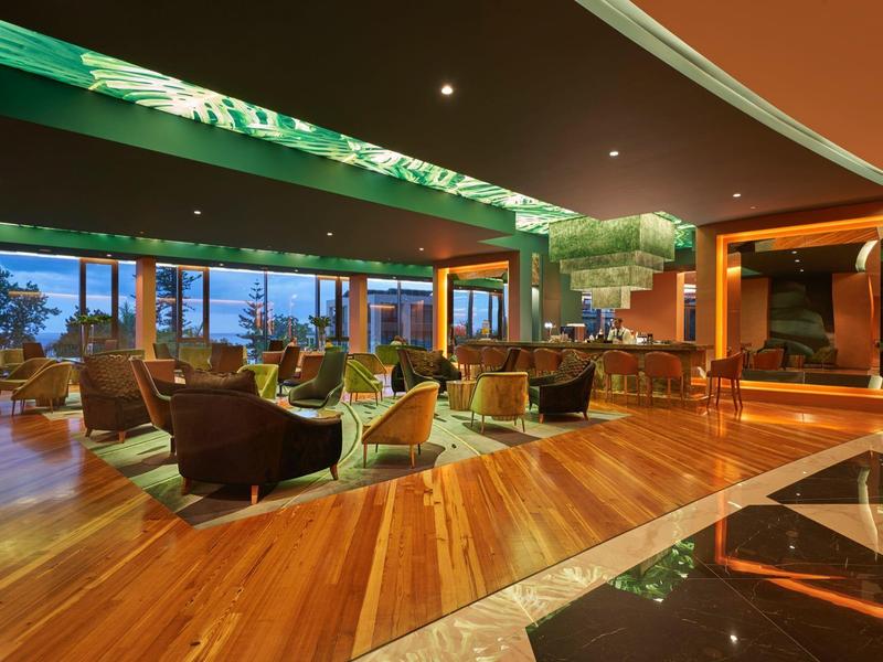 Elegantní hotelová recepce s dřevěnou podlahou a stylovým sezením při večerním osvětlení.