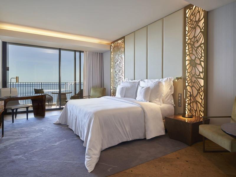 Moderní hotelový pokoj s velkou postelí, balkonem a výhledem na moře za denního světla
